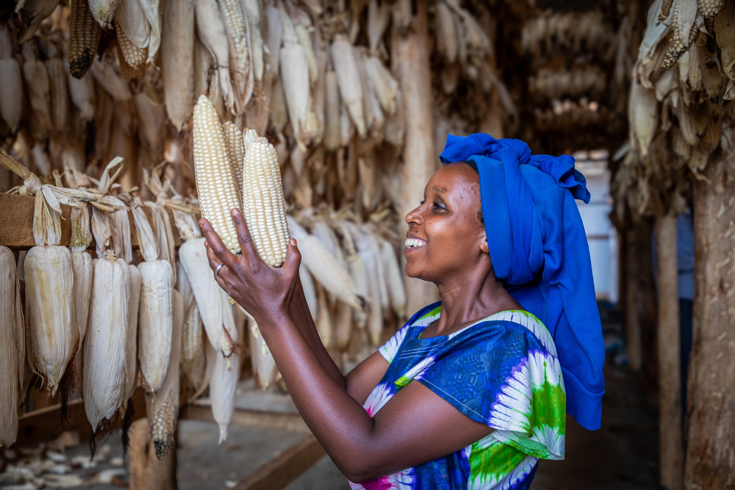 Rwanda. Refugee smallholder farmer showcasing their maize harvest in the new drying shade, built with WFP's support
